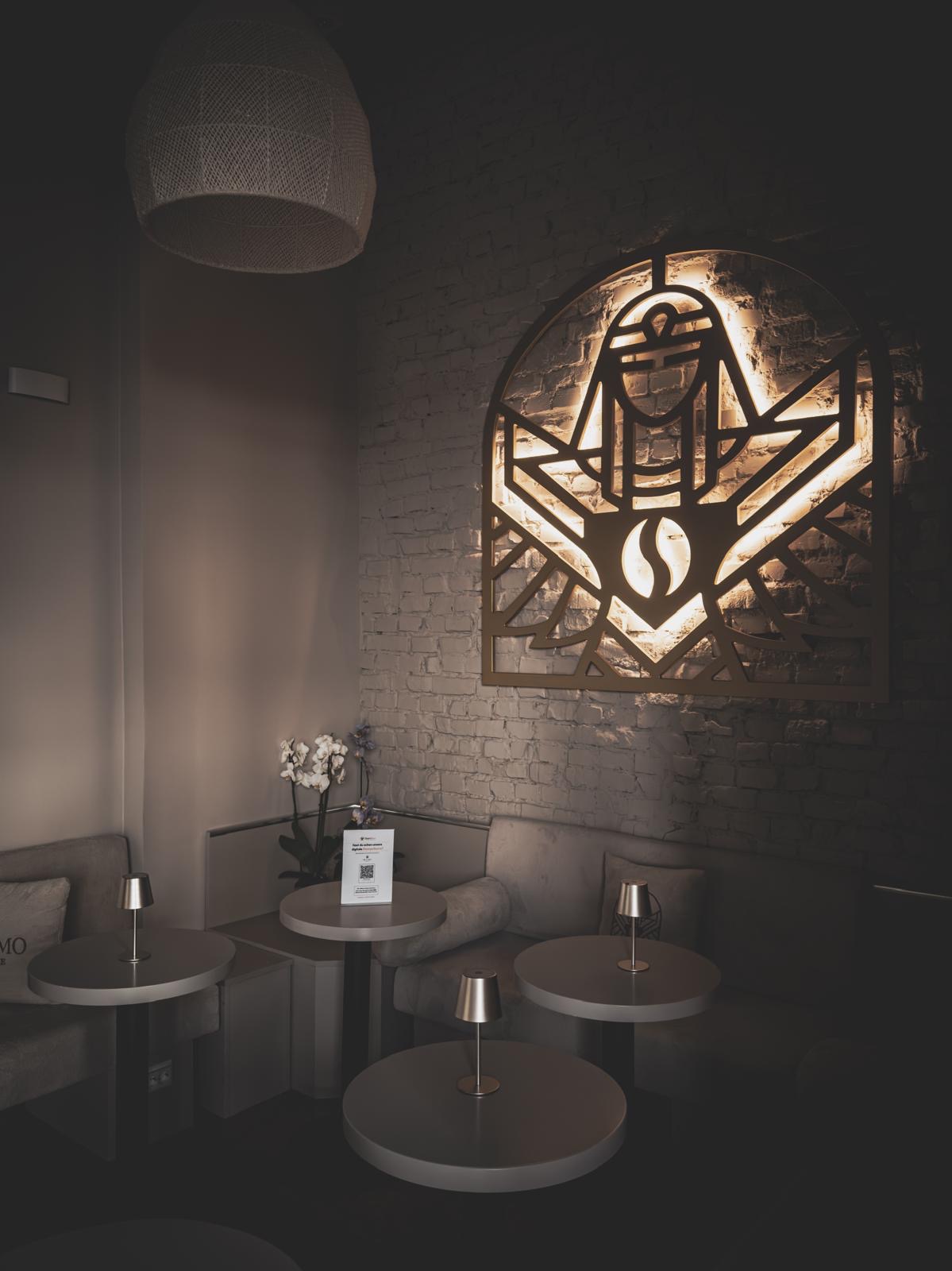 Innenraum des ME & MO Cafés mit beleuchtetem goldenem Pharao-Wandbild